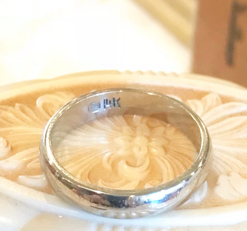 May include: A silver wedding band with a 14K marking on the inside of the band.