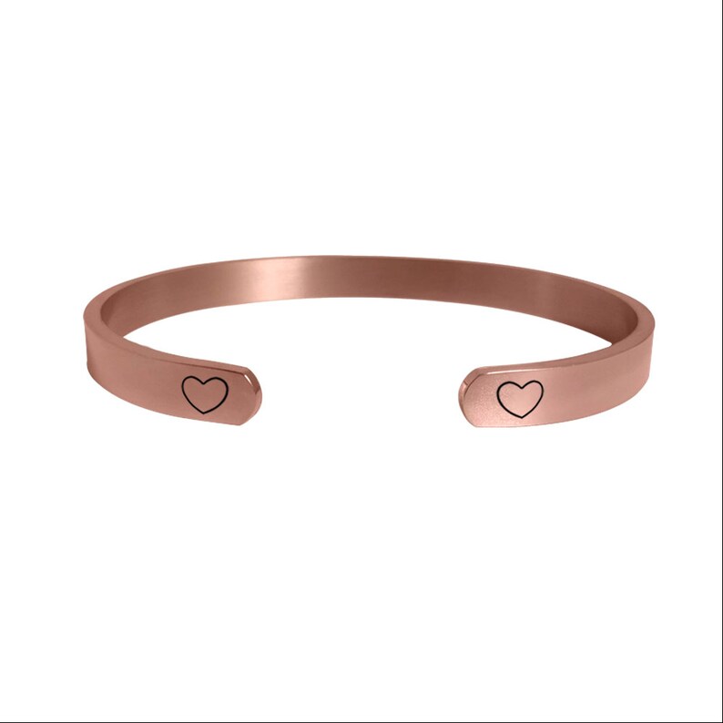 May include: A rose gold cuff bracelet with two small heart cutouts on each end.