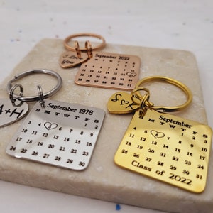 May include: Three gold keychains with a heart charm and a calendar charm. The calendar charms feature the months of September 1978, September 2022, and the text "Class of 2022".