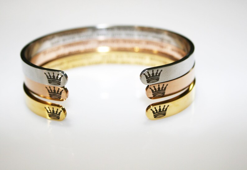 May include: Three stacked bracelets with a crown design on each end. The bracelets are silver, rose gold, and gold.