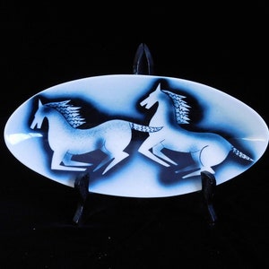 May include: White ceramic oval serving dish with a black and white design of two stylized horses running. The dish is on a black stand.