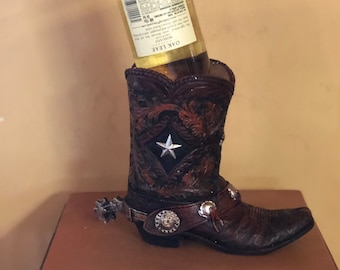 Un divertido soporte para botellas de vino con forma de bota, pintado con gran detalle. Será una hermosa decoración para tu bar.
