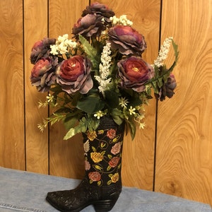 Bota negra con hermoso aspecto de cuero repujado cubierto de rosas de múltiples colores, Arreglo floral de rosas flores blancas y vegetación