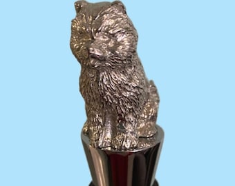May include: Silver bottle stopper with a detailed sculpture of a fluffy dog sitting on top.