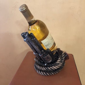 銃、ピストル、リボルバー、そしてロープをモチーフにしたワインホルダーが美しくペイントされています。バーを美しく飾るのに最適です。