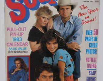 Op de afbeelding: Een tijdschriftcover met een groep van vier mensen, waaronder twee vrouwen en twee mannen. Het tijdschrift heet "Soapersar" en de tekst op de cover luidt "Het nieuwe jaar in de soaps!" en "Meer dan 50 pagina's met kleurenfoto's!" De tijdschriftcover bevat ook een uitneembare kalender voor 1983.