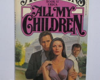 Op de afbeelding: Boekomslag voor "All My Children", boek twee van de serie "Agnes Nixon's Erica". De omslag toont een stel dat elkaar omhelst voor een groot huis, met een man die achter hen staat. De tekst op de omslag luidt "PINE VALLEY IS A PLACE THAT NEVER LETS YOU GO... AGNES NIXON'S BOOK II ERICA ALL MY CHILDREN A NOVEL BY ROSEMARIE SANTINI"