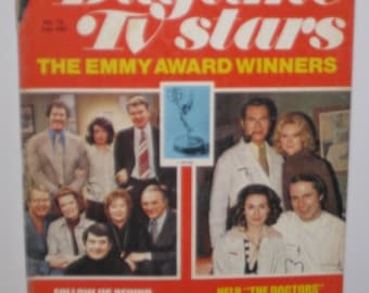 Op de afbeelding: Een tijdschriftcover met een groep acteurs uit de dagtelevisieshows "The Edge of Night" en "The Doctors". De omslag is rood en geel met de titel "Daytime TV Stars" en de tekst "The Emmy Award Winners".