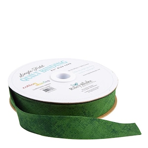 May include: A spool of green bias tape for quilting. The label reads "Single Fold Quilt Binding" and "Christmas Green." The tape is 2.5 inches wide and made by Riley Blake Designs. The tape is a solid green color with a textured appearance.