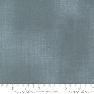 May include: A close-up of a piece of fabric in a muted teal color. The fabric has a subtle texture and a grid-like pattern. A ruler is at the bottom of the image, with measurements in inches.