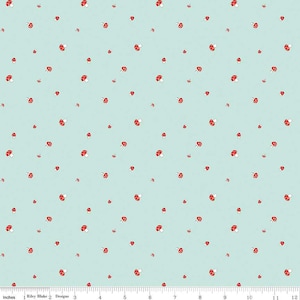 May include: A light blue fabric with a repeating pattern of red and white mushrooms. The mushrooms are scattered across the surface. The fabric is measured in inches.
