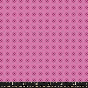 May include: Pink fabric with a repeating pattern of small, dark pink polka dots. The fabric has a solid pink background. The bottom of the image has a black ruler with white markings and text that reads "RUBY STAR SOCIETY".