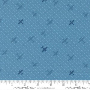 May include: Blue fabric with a pattern of dark blue airplanes and white dotted lines. The airplanes are evenly spaced across the fabric. The fabric has a ruler along the bottom edge.