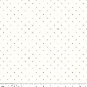 May include: Cream-colored fabric with a repeating pattern of small, gray crosses. The crosses are evenly spaced across the surface. A ruler with inch measurements is visible along the bottom edge of the fabric.