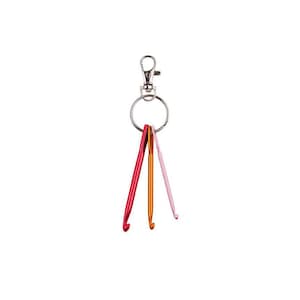 May include: A keychain with three colorful crochet hooks. The hooks are in shades of red, orange, and pink. The keychain has a silver clasp and a ring to attach keys.