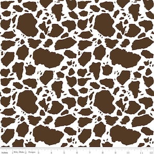 May include: A fabric print featuring a repeating pattern of irregular dark brown shapes on a solid white background. A ruler is visible at the bottom edge, showing measurements in inches from 0 to 12, with the text Riley Blake Designs.