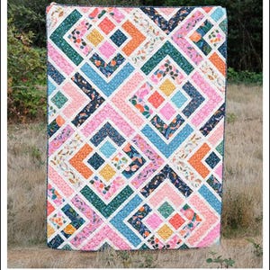 May include: A colorful quilt with a geometric pattern. The quilt features a variety of colors including pink, blue, orange, green, and yellow. The text "The Penny Quilt" and "A Pattern by Erica Jackman" are visible. The quilt is designed for baby, lap, and twin sizes.