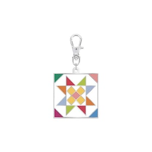 May include: A silver keychain with a colorful patchwork quilt design. The quilt is made up of triangles and squares in shades of pink, blue, green, yellow, and orange. The keychain has a silver loop for attaching to keys.