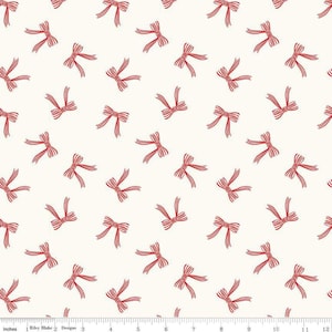 May include: Cream-colored fabric with a repeating pattern of red bows. The bows are evenly spaced across the fabric, with each bow featuring a detailed design. The fabric is measured in inches along the bottom edge.