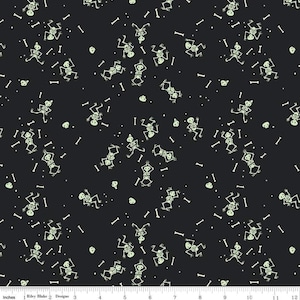 May include: Black fabric with a repeating pattern of glowing green skeletons, bones, and small white dots. The skeletons are in various poses, with some appearing to be dancing or doing yoga. The fabric is marked with inches.