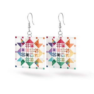 May include: A pair of silver earrings with a colorful patchwork quilt design. The earrings are square shaped and feature a variety of colors and patterns.