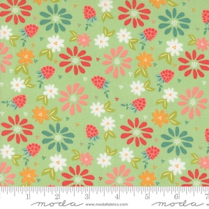 May include: A green fabric with a repeating pattern of red, pink, white, and teal flowers and small red strawberries. The fabric has a ruler with the word "moda" printed on it.