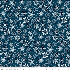 May include: A fabric with a repeating pattern of white and light blue snowflakes on a dark blue background. The snowflakes vary in size and design, creating a wintery or holiday theme. The fabric is measured in inches.