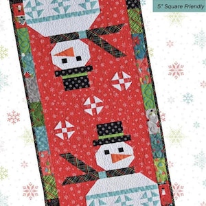 May include: A rectangular quilt runner featuring two snowmen on a red background with white snowflake patterns. The snowmen wear black polka-dot hats and plaid scarves. The border consists of multi-colored fabric squares. Text reads Mr Frosty.