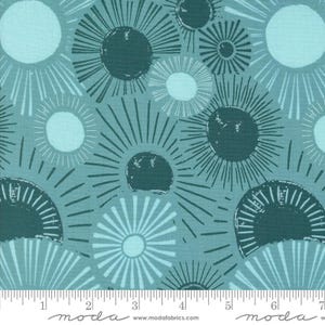 May include: Teal and light blue fabric with a repeating pattern of stylized suns with radiating lines. The fabric is marked with a ruler in inches and the words "moda" and "www.modafabrics.com".
