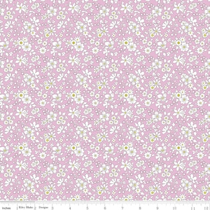 May include: Pink fabric with a repeating floral pattern. White flowers with yellow centers and green stems are scattered across the pink background. The fabric is marked with inches along the bottom edge.
