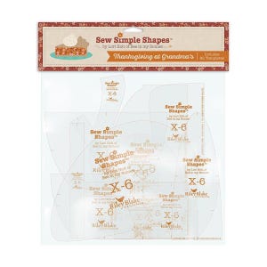 May include: A package of Sew Simple Shapes by Lori Holt of Bee in my Bonnet titled Thanksgiving at Grandma's. The clear plastic set includes 82 templates for quilting and sewing projects, featuring various curved and straight shapes with markings.