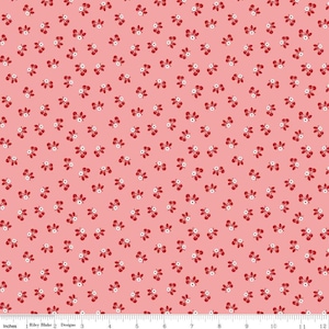 May include: Pink fabric with a repeating pattern of small red cherries with white centers. The cherries are arranged in a diagonal pattern.