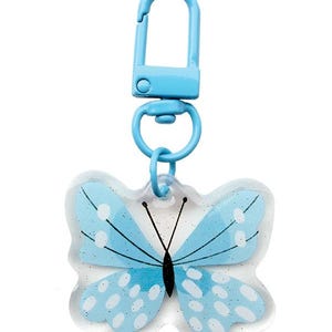 May include: A light blue butterfly keychain with a white glitter design and a blue metal clasp.