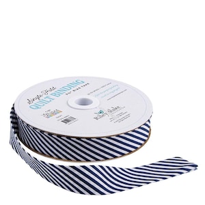 May include: A spool of navy and white striped single-fold quilt binding tape. The tape is 1/8" wide and is labeled "Riley Blake Designs". The spool is white with blue text that reads "Single Fold Quilt Binding".