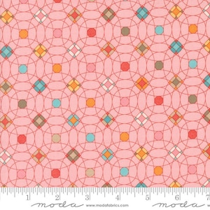 May include: Pink fabric with a repeating pattern of red circles, orange, blue, and brown diamonds, and white lines. The fabric is measured with a ruler in inches.