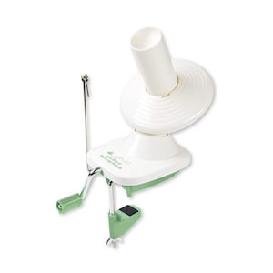 May include: A white and green yarn winder with a crank handle and a clamp for securing it to a table. The winder has a cylindrical top and a base with a green accent. The text "Love Knitters" is printed on the base.