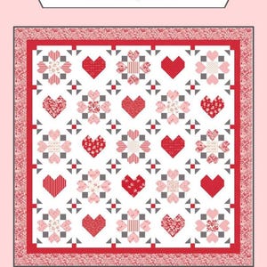 May include: A quilt with a white background featuring red hearts and floral patterns. The quilt is framed with a red border and the text "Sew-N-Quilt" and "Surrounded By Love".
