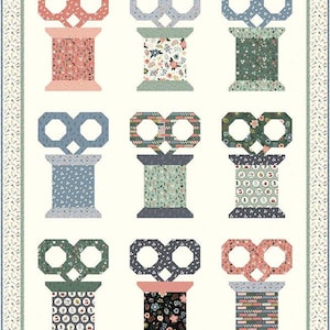 May include: Nine colorful spools of thread with different patterns and colors. Each spool has a pair of scissors on top. The spools are arranged in three rows of three.