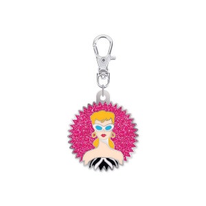 May include: A silver keychain with a pink glitter background and a cartoon image of a blonde woman wearing sunglasses and a black and white striped dress.
