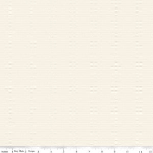 May include: Cream-colored fabric with a subtle dotted pattern. The image includes a ruler along the bottom edge, marked in inches, with the text "Riley Blake Designs". This fabric is suitable for various sewing and crafting projects.
