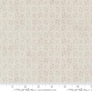 May include: A white fabric with a subtle, repeating pattern of small, white flowers on a light gray background. The fabric is shown with a ruler for scale.