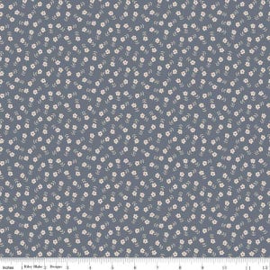 May include: A fabric with a repeating pattern of small, white flowers and green stems on a blue-gray background. The fabric is marked with inch measurements along the bottom edge. The Riley Blake Designs logo is visible.