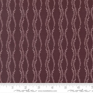 May include: A dark maroon fabric featuring a repeating vertical pattern of light pink wavy vines with small leaves. A white ruler is visible at the bottom edge, showing measurements in inches from 0 to 7, with the text moda www.modafabrics.com.