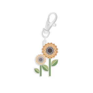 May include: A silver keychain with a charm featuring two stylized sunflowers with green leaves. The larger sunflower is orange and brown, while the smaller sunflower is beige and brown.