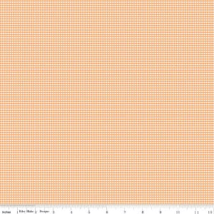 May include: A peach-colored fabric with a fine white gingham pattern. The fabric is shown on a ruler with inches marked.