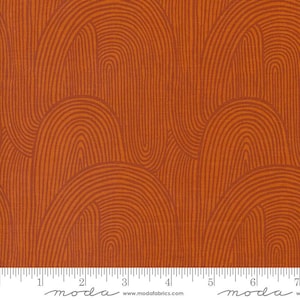 May include: Close-up of orange fabric with a repeating pattern of curved lines resembling arches. The lines are a darker shade of orange, creating a textured effect. The fabric has a ruler along the bottom edge.
