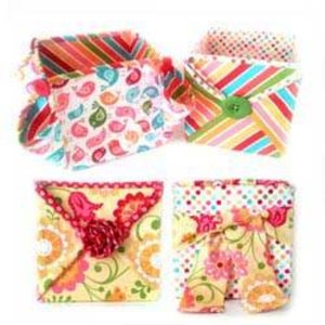 May include: Four fabric boxes with different patterns. The boxes are folded and have a square shape. The patterns include birds, polka dots, stripes, and floral designs. The boxes are made of colorful fabric and are perfect for storing small items.