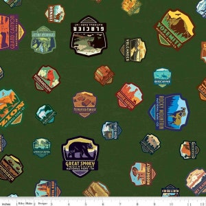 May include: A green fabric with a repeating pattern of colorful national park patches. The patches feature names and logos of various national parks, including Yosemite, Glacier, Zion, and Great Smoky Mountains.
