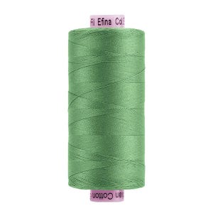 May include: A spool of sage green sewing thread with a smooth, matte finish. The spool features light pink end caps with printed text that reads Fil Efina Col. and Cotton. The thread is wound tightly around the cylindrical plastic core.