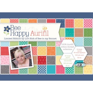 May include: A colorful quilt pattern featuring a bee and the text "Bee Happy Aurifil" with the words "Limited Edition by Lori Holt of Bee in my Bonnet". The image also includes a photo of Lori Holt and details about the 100% cotton thread collection.